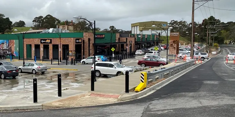 Automotive Safety Engineering energy absorbing bollard installation at a retail centre car park, with foreground pedestrian protection bollards and a yellow EAB unit on the right.
